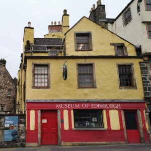 Photo of a building painted red and yellow, with 'Museum of Edinburgh' signage in white letters.