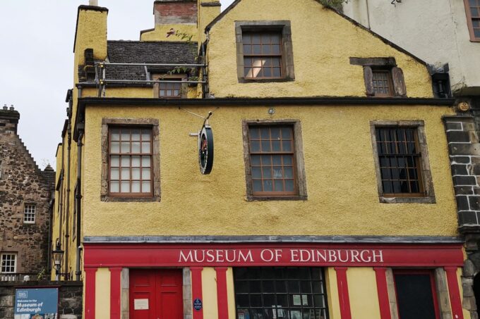 Photo of a building painted red and yellow, with 'Museum of Edinburgh' signage in white letters.