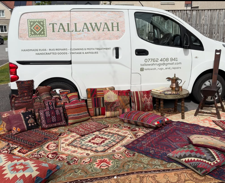 A selection of handmade Turkish and North African rugs and cushions, plus some antique furniture in front of a white van, branded with the Tallawah Rugs and Repairs logo